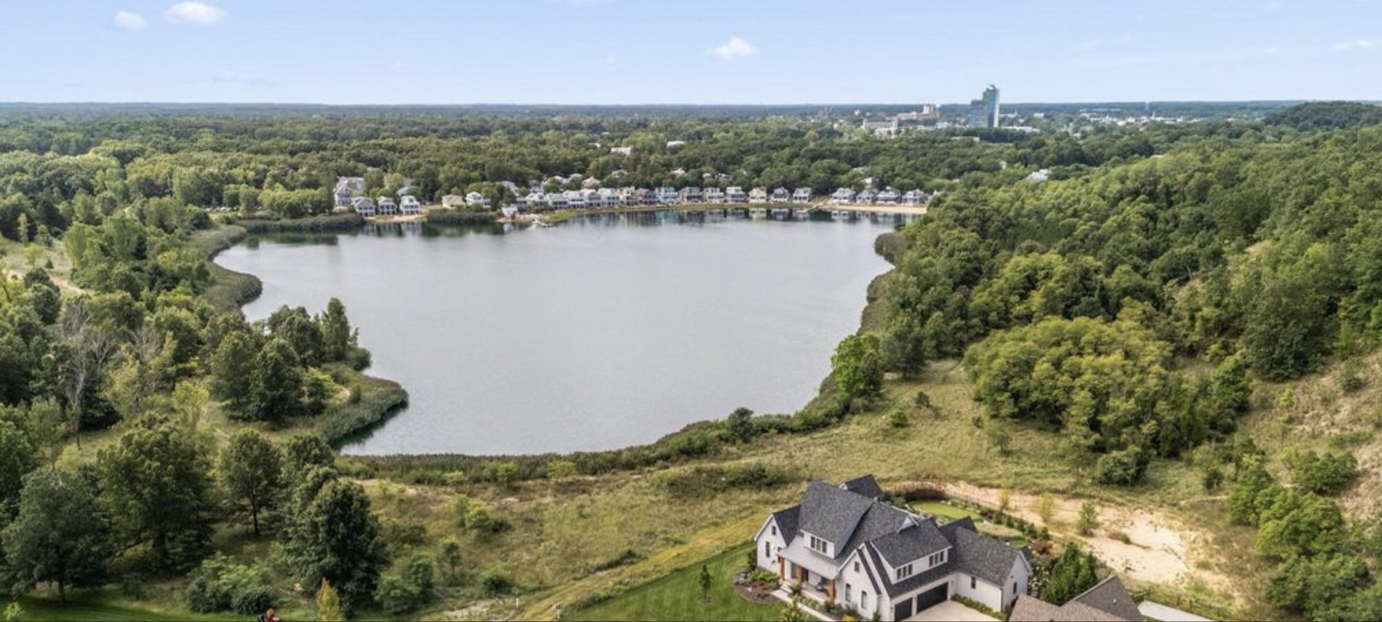 Lake Kai aerial — the private 23.930-acre modeled lake at the heart of Indiana Dunes Club, with the Beachwalk community visible on the north shore and downtown Michigan City on the horizon.